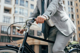 partial view of businessman in suit biking in city