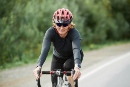 Young sportswoman in helmet riding on her bike on a road in the countryside