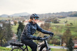 A side view of active senior woman with electrobike cycling outdoors in countryside in autumn.