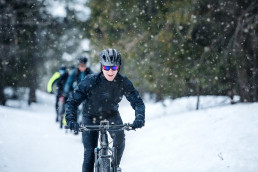 A group of young mountain bikers riding on road outdoors in winter.